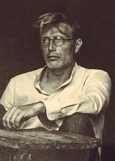 a black and white photo of a man sitting at a table with his arms crossed