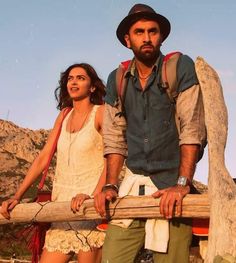 a man and woman standing next to each other holding a wooden stick in their hands