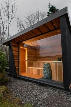 an outdoor sauna in the middle of a wooded area with rocks and grass on the ground