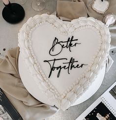 a heart - shaped cake with the words better together written on it, surrounded by other items