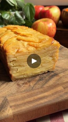 an apple pie on a cutting board with apples in the background