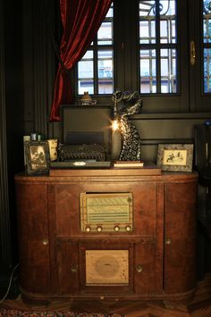 an old fashioned radio sitting on top of a wooden cabinet in front of a window