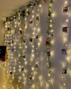 there is a wall with pictures and lights hanging on the wall, along with flowers