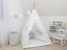 a child's teepee with stars hanging from the ceiling in a white room