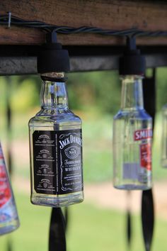 several bottles are hanging from a wooden beam