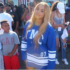 a woman standing next to two boys in front of a group of people wearing baseball caps