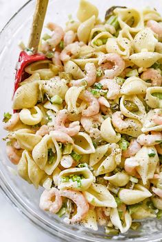 pasta salad with shrimp and broccoli in a glass bowl on a white surface