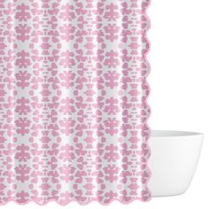 a pink and white shower curtain with scalloped edge on a white bowl in front of it