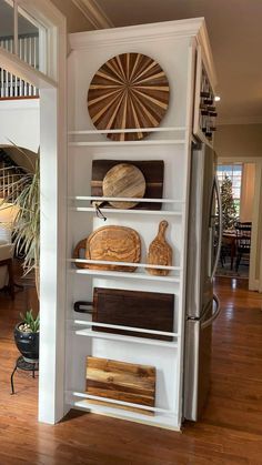 a kitchen with white shelves and wooden cutting boards on top of them in front of a staircase