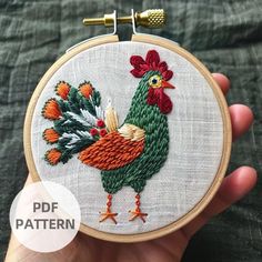 a hand holding a small embroideryed rooster