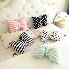 several pillows and bows on a bed with white headboard in the background, including one for children's bedroom