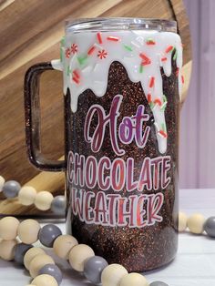 a frosted mug with hot chocolate and sprinkles on it next to candy