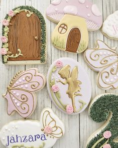 some decorated cookies are laying on a white wooden table and there is a fairy door in the background