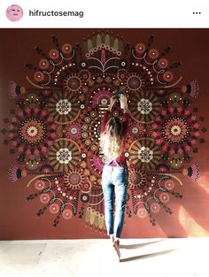 a woman standing in front of a wall hanging on the side of a red wall