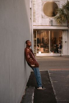 a man leaning against the side of a building