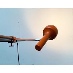 an orange light hanging from the side of a white wall with a wooden pole attached to it