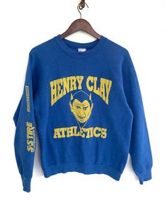 "Vintage Henry Clay Athletics  Stain ( Refer pictures ) Sw110 Measurements: Width (armpit to armpit): 21\" Length (shoulder to end of garment):  25.5\" All measurements are taken with the garment flat on the ground. Refer picture carefully  Condition: Stain THANK YOU" Retro Crew Neck Pre-shrunk Top, Vintage Pre-shrunk Sweatshirt For Fan Merchandise, Vintage Pre-shrunk Sweatshirt For Fans, Pre-shrunk Vintage Sweatshirt For Fans, Retro Cotton Pre-shrunk Sweatshirt, Retro Blue Sweatshirt With Screen Print, Retro Cotton Sweatshirt With Screen Print, Vintage Graphic Print Winter Top, Retro Relaxed Fit T-shirt