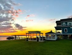 a gazebo sitting on top of a lush green field next to the ocean