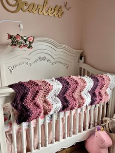 a crocheted blanket is hanging on the side of a baby's crib