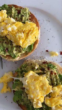 two open faced sandwiches with eggs and avocado on them, sitting on a white plate