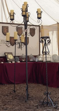 a group of candles sitting on top of a metal pole next to a red table cloth