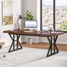 a wooden desk with two laptops on it in front of a large window overlooking the city