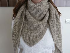 a woman wearing a knitted scarf in front of a refrigerator