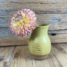 a green vase with a pink flower in it