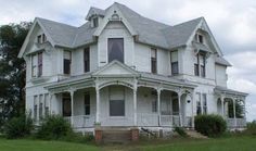 an old white house sitting on top of a lush green field