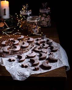 a table topped with lots of pastries on top of a wooden table next to candles