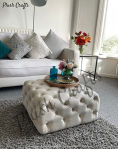 a living room with a white couch, coffee table and flowers in vases on the floor