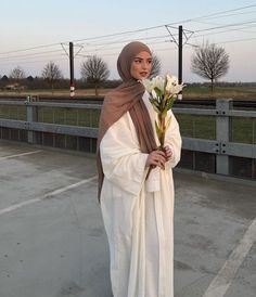 a woman wearing a hijab and holding flowers