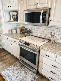 a stove top oven sitting inside of a kitchen next to white cupboards and counter tops