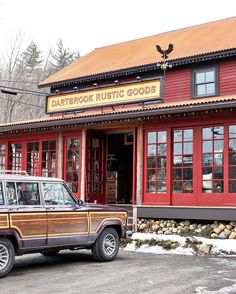 a jeep is parked in front of a red building with wood trim and windows on it