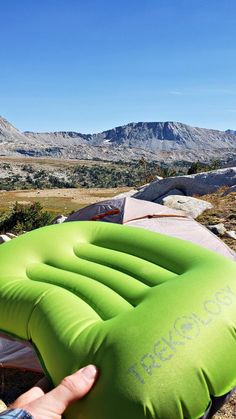 an inflatable mattress sitting on top of a mountain next to a person's hand