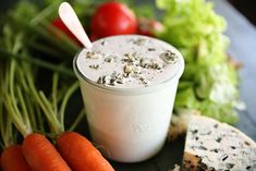 carrots, celery and cheese on a plate next to a cup of yogurt