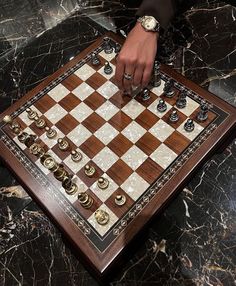 a person is playing chess on a marble table