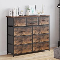 a dresser with drawers and pictures on it in a room next to a window,