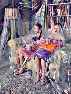 two women sitting on a couch covered in plastic