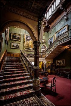 an ornate staircase in a building with paintings on the walls and carpeted flooring