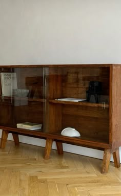 a wooden bookcase sitting on top of a hard wood floor next to a white wall