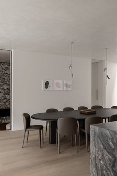 a dining room table and chairs in front of a wall with art work on it