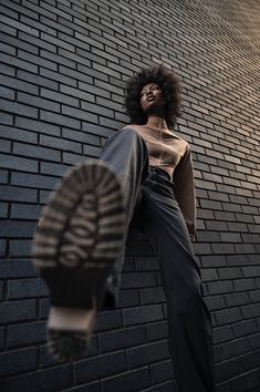 a woman leaning up against a brick wall