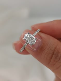 a woman's hand holding a diamond ring