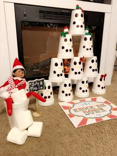 an elf is sitting in front of a christmas tree made out of toilet paper cups