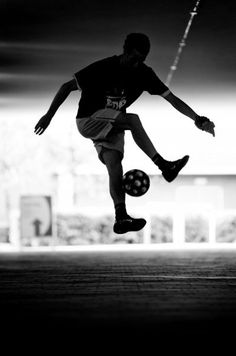 a man kicking a soccer ball on top of a field