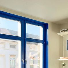 a room with two windows and a blue door