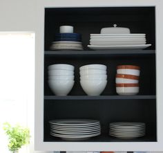 white dishes and plates sit on shelves in a kitchen