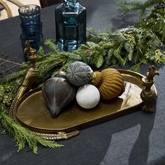 an assortment of seashells on a tray with pine branches and candles in the background