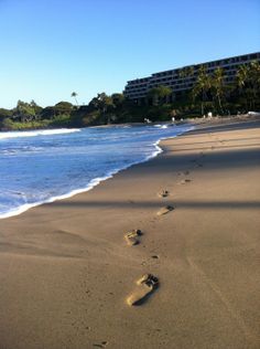 footprints in the sand on a beach with buildings in the background